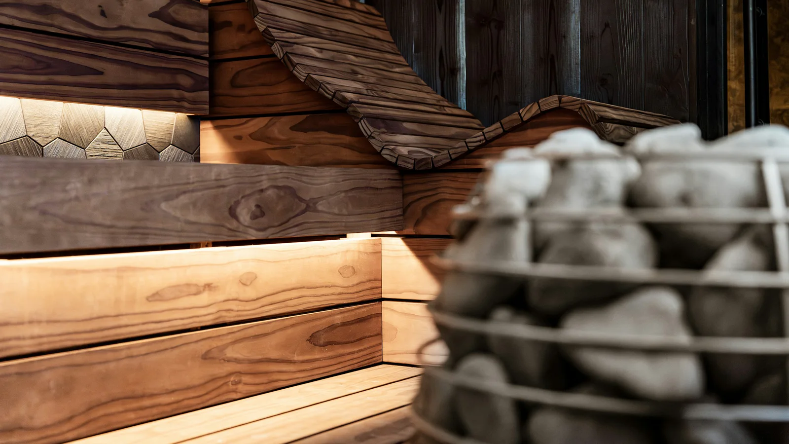 Official HUUM photograph of a modern wooden sauna interior and stone heater